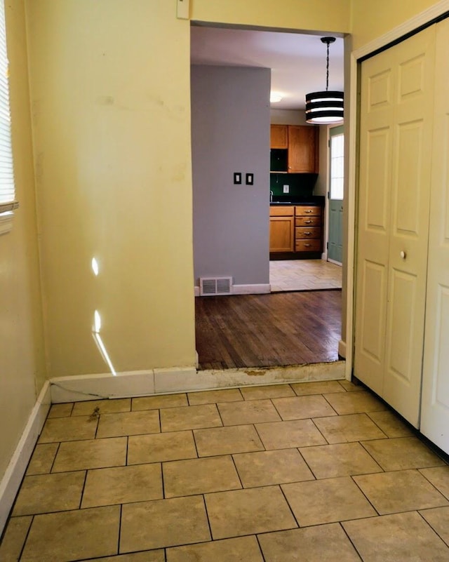 interior space with light tile patterned flooring, visible vents, and baseboards