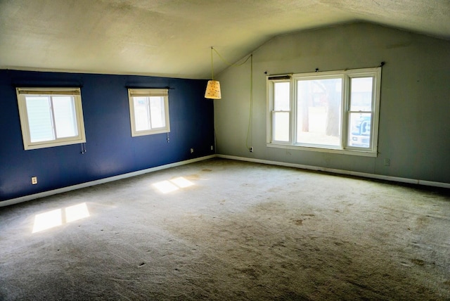 spare room featuring a textured ceiling, baseboards, carpet, and vaulted ceiling