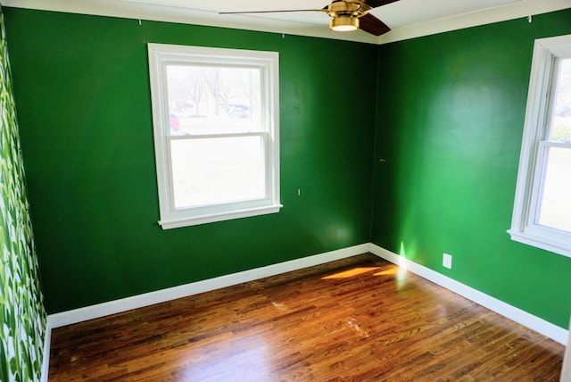 spare room featuring dark wood finished floors, ceiling fan, and baseboards