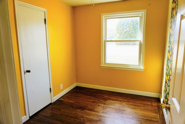 empty room featuring dark wood-style floors and baseboards