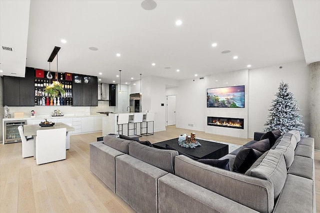 living area featuring beverage cooler, recessed lighting, and light wood-style floors