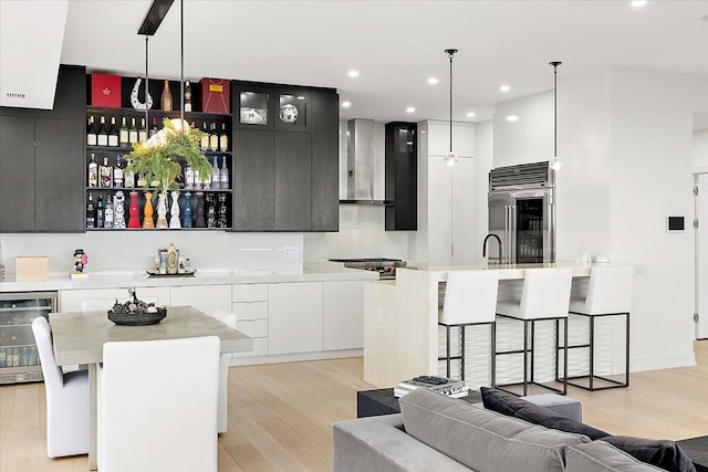 kitchen featuring stainless steel built in fridge, light countertops, wine cooler, wall chimney exhaust hood, and modern cabinets