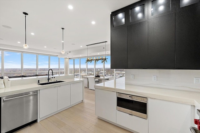 kitchen with dark cabinetry, a sink, light countertops, appliances with stainless steel finishes, and modern cabinets