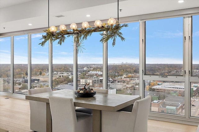 unfurnished dining area with light wood-type flooring, a view of city, visible vents, and floor to ceiling windows