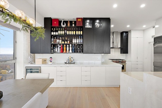 interior space with beverage cooler, wall chimney range hood, high end stainless steel range oven, and modern cabinets