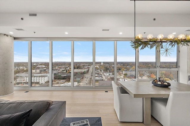 dining room with floor to ceiling windows, light wood-style flooring, and visible vents