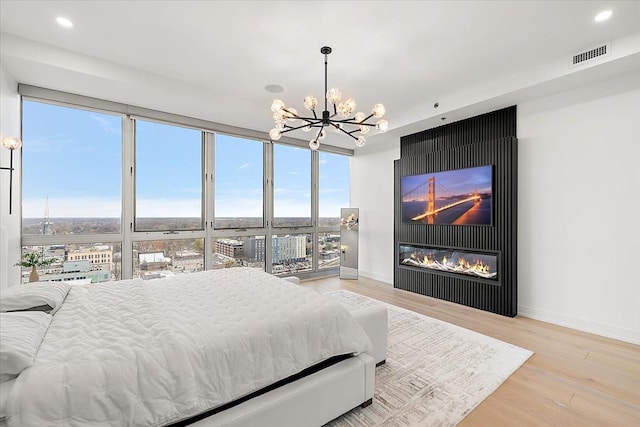 bedroom with wood finished floors, visible vents, baseboards, recessed lighting, and a chandelier