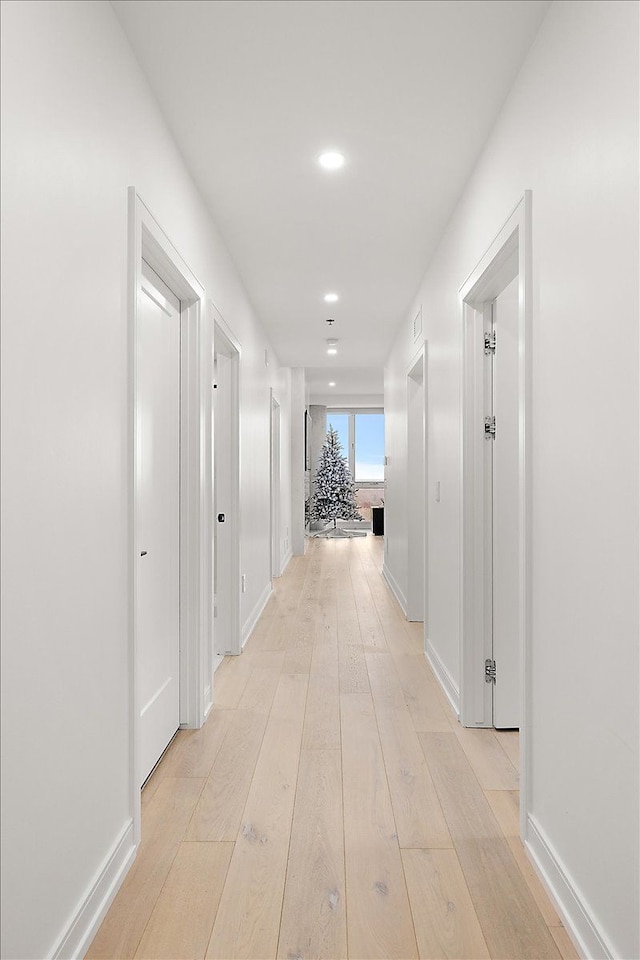 hallway with recessed lighting, baseboards, and light wood finished floors