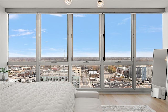 unfurnished bedroom featuring a wall of windows, a city view, and wood finished floors