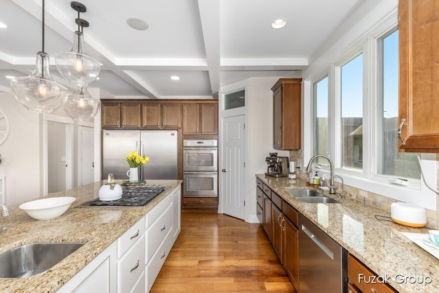 kitchen featuring a sink, stainless steel appliances, pendant lighting, and light wood-style flooring