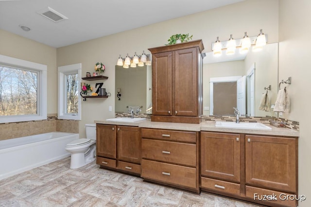 full bath featuring visible vents, a washtub, toilet, and a sink