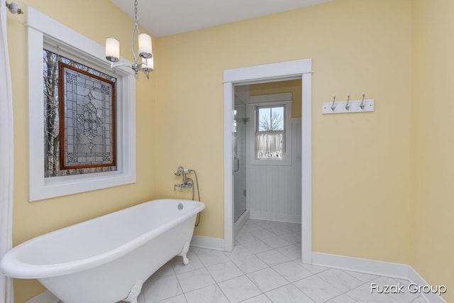 full bath featuring a shower stall, a freestanding tub, and baseboards