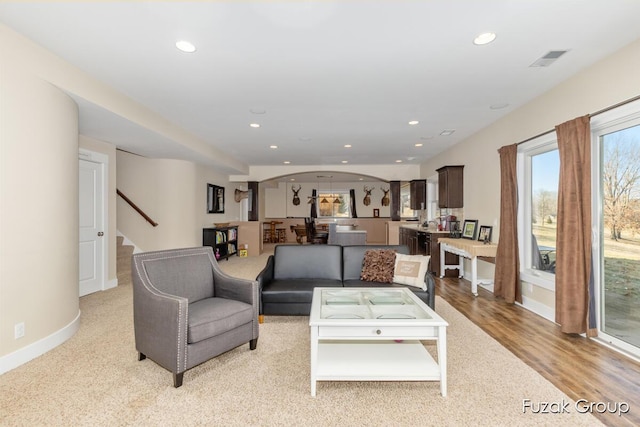 living area with visible vents, baseboards, light wood-style flooring, recessed lighting, and stairs