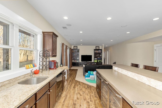 kitchen with light stone countertops, visible vents, recessed lighting, a sink, and light wood-style floors