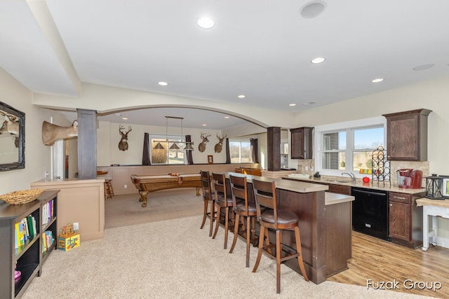 kitchen featuring dark brown cabinetry, dishwasher, a breakfast bar, and a center island