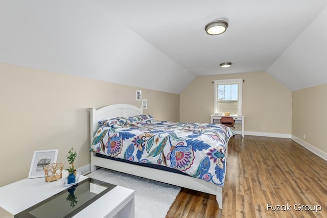 bedroom featuring vaulted ceiling, wood finished floors, and baseboards