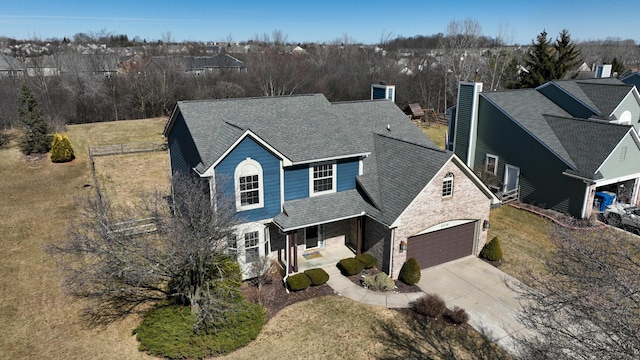 traditional-style home featuring a porch, concrete driveway, a front yard, a shingled roof, and a chimney