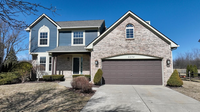 traditional-style home featuring fence, a shingled roof, concrete driveway, a garage, and brick siding