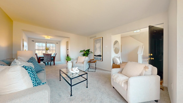 living area with baseboards, visible vents, and light carpet