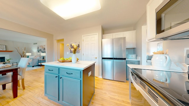 kitchen featuring blue cabinetry, stainless steel appliances, light wood-style flooring, and light countertops