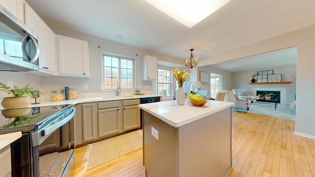 kitchen featuring stainless steel microwave, light wood-style flooring, electric stove, a notable chandelier, and a sink