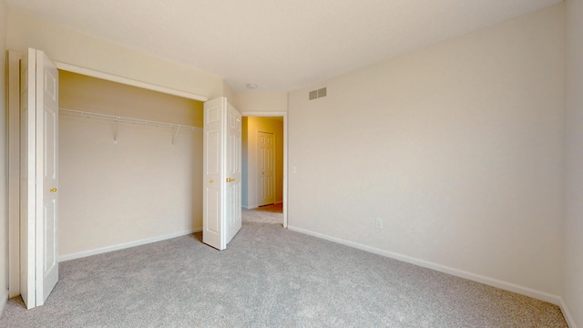 unfurnished bedroom featuring a closet, visible vents, light colored carpet, and baseboards