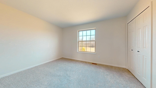 unfurnished bedroom featuring visible vents, baseboards, a closet, and light carpet