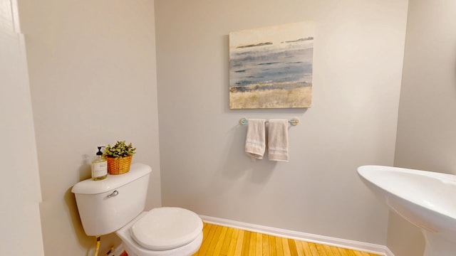 half bath featuring toilet, baseboards, and wood finished floors