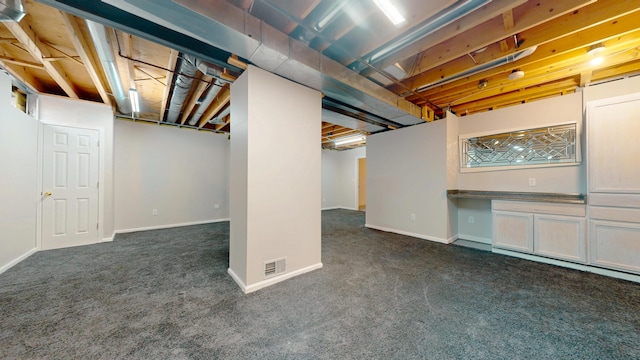 finished basement featuring visible vents, baseboards, and dark carpet