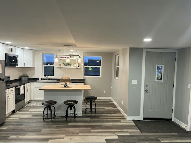 kitchen featuring a breakfast bar area, wooden counters, a sink, white cabinets, and appliances with stainless steel finishes