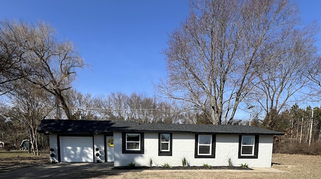 ranch-style home with a garage and a shingled roof