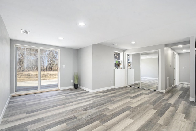 unfurnished living room with recessed lighting, visible vents, baseboards, and wood finished floors