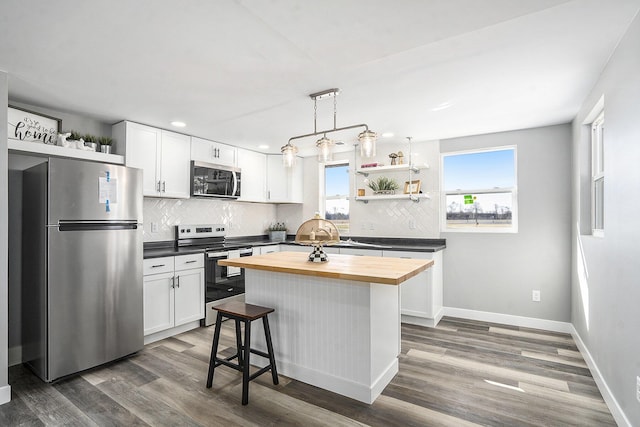 kitchen featuring a wealth of natural light, dark wood-type flooring, white cabinetry, stainless steel appliances, and butcher block counters