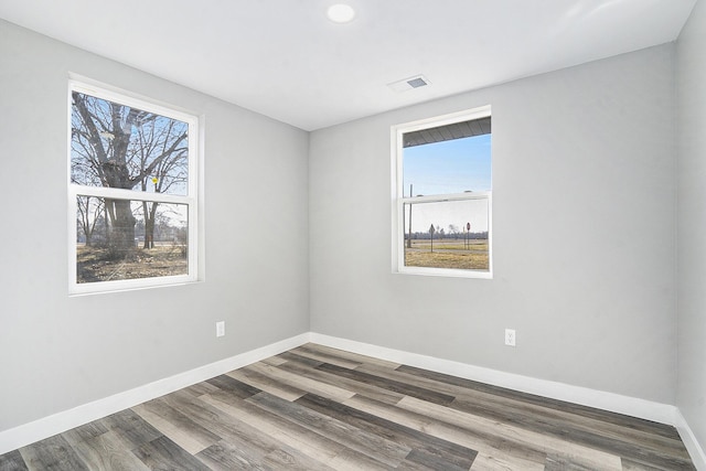 unfurnished room with visible vents, baseboards, and wood finished floors