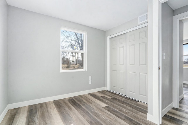 unfurnished bedroom featuring a closet, baseboards, visible vents, and dark wood-style flooring