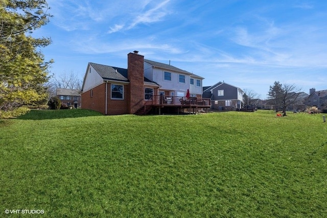 back of property featuring a deck, a yard, and a chimney