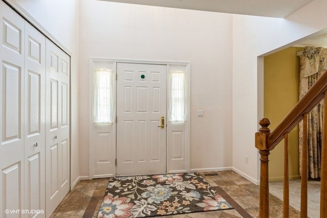 entrance foyer with stairway, stone finish floor, and baseboards