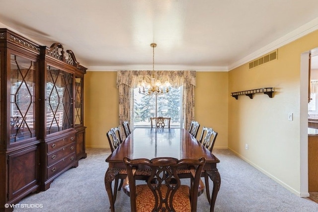 dining room featuring visible vents, ornamental molding, an inviting chandelier, baseboards, and light colored carpet