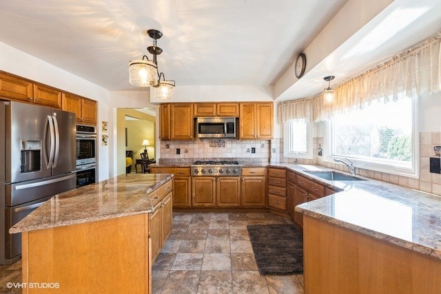 kitchen with a sink, light stone counters, tasteful backsplash, appliances with stainless steel finishes, and brown cabinetry