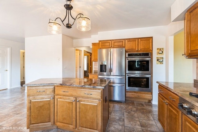 kitchen with dark stone counters, brown cabinets, appliances with stainless steel finishes, and a center island