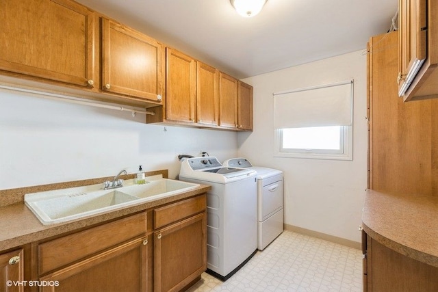 clothes washing area featuring independent washer and dryer, a sink, cabinet space, baseboards, and light floors