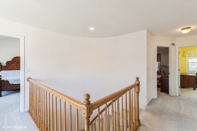 hall with recessed lighting, baseboards, an upstairs landing, and light carpet