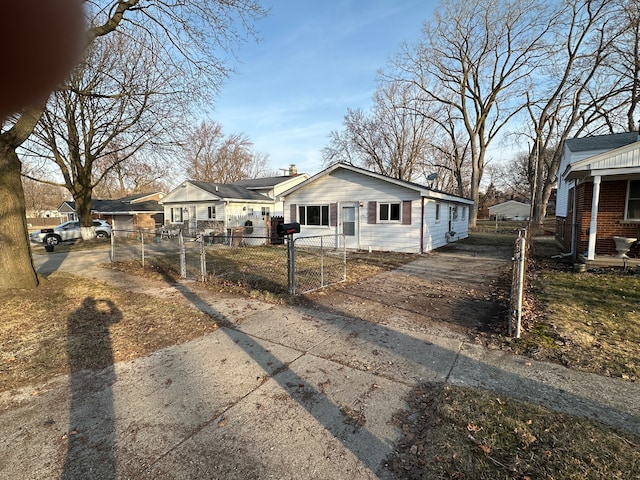 bungalow-style home featuring a fenced front yard, concrete driveway, and a gate