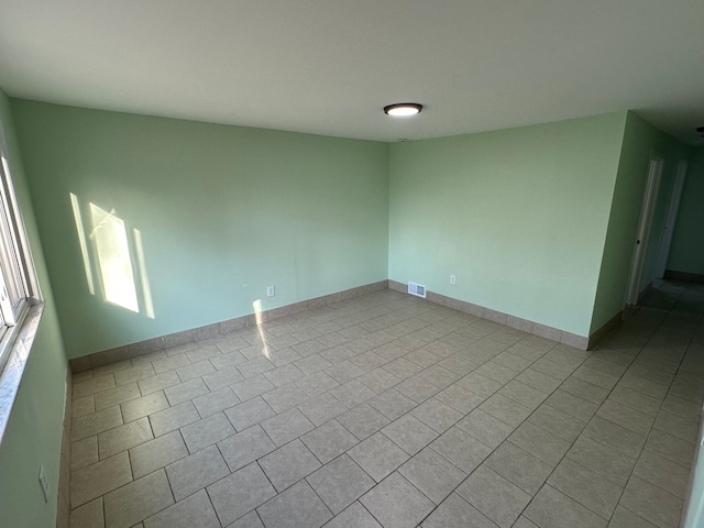 spare room with tile patterned flooring, baseboards, and visible vents