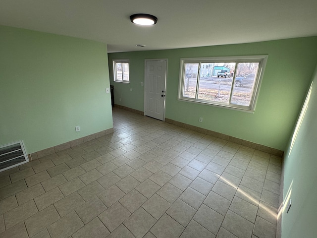 spare room with tile patterned floors, visible vents, and baseboards