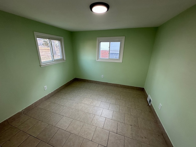 unfurnished room featuring tile patterned floors, plenty of natural light, visible vents, and baseboards