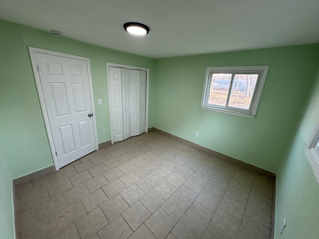 unfurnished bedroom with a closet, baseboards, and tile patterned flooring