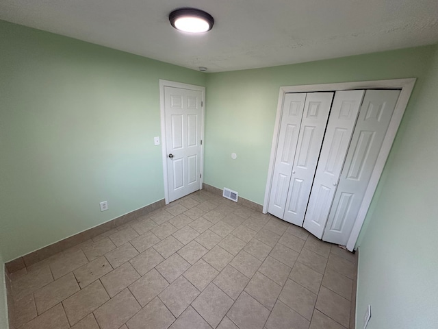 unfurnished bedroom with baseboards, visible vents, and a closet