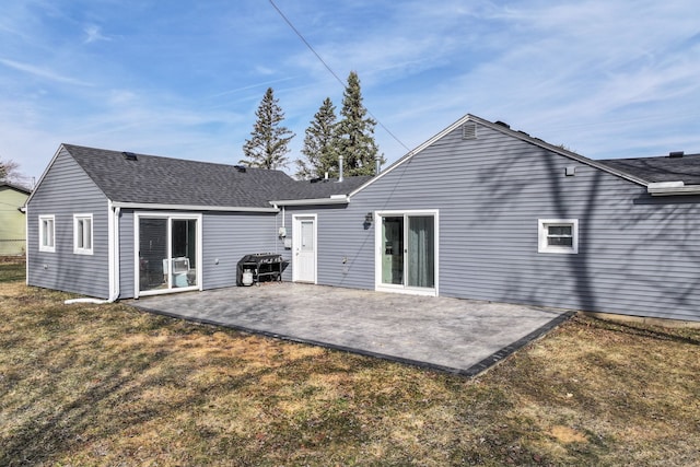 rear view of property with a patio, a lawn, and a shingled roof