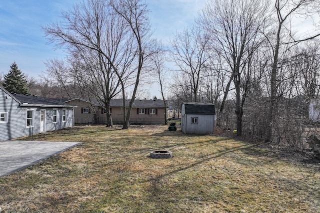 view of yard featuring a storage unit, a patio, an outdoor structure, and an outdoor fire pit